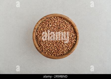 Raw  buckwheat in wooden bowl  on concrete background. Top view Stock Photo