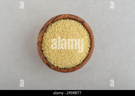 Raw couscous  in wooden bowl  on concrete background. Top view Stock Photo