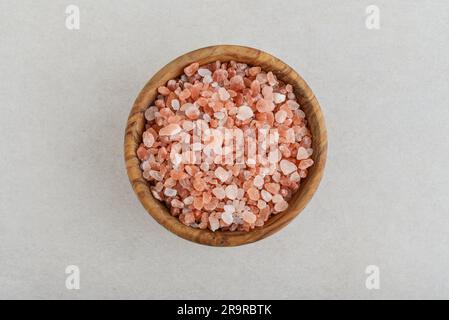 Pink Himalayan coarse grain salt in wooden bowl  on concrete background. Top view Stock Photo