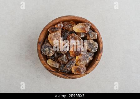 Large caramelized sugar in wooden bowl on concrete background. Top view Stock Photo