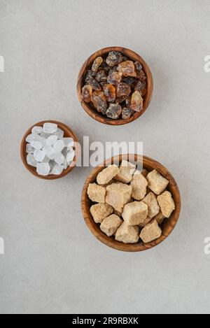 Three different types of sugar in wooden bowls on concrete background. Top view Stock Photo
