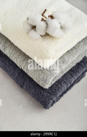 Stack of bath towels with cotton flowers on light concrete background closeup Stock Photo