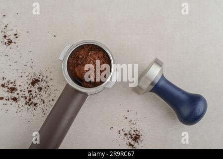 Portafilter with coffee and temper on light concrete background top view Stock Photo