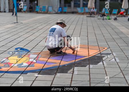 Kaiserslautern, Germany. 28th June, 2023. Milivoj Kostic making progress at the end of day 1. Eleven international artists from 6 countries are turning the Stiftsplatz (Square) pavement into three-dimensional art. 3D street art uses perspective to create optical illusion of space. Visitors are welcome to watch all artists at work over three days from Wednesday at 8:00 AM to Friday 6:00 PM. This years topic is 'Digitalisation and Smart City'. Paintings will depict robots, data, or cyberpunk scenarios. Credit: Gustav Zygmund/Alamy News Stock Photo