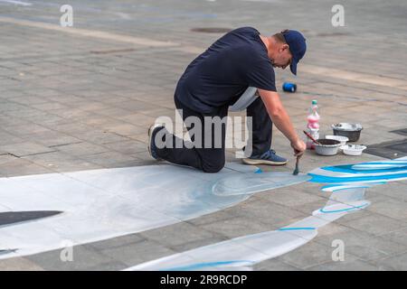 Kaiserslautern, Germany. 28th June, 2023. Nikolaj Arndt painting after several hours at the end of day one. Eleven international artists from 6 countries are turning the Stiftsplatz (Square) pavement into three-dimensional art. 3D street art uses perspective to create optical illusion of space. Visitors are welcome to watch all artists at work over three days from Wednesday at 8:00 AM to Friday 6:00 PM. This years topic is 'Digitalisation and Smart City'. Paintings will depict robots, data, or cyberpunk scenarios. Credit: Gustav Zygmund/Alamy News Stock Photo