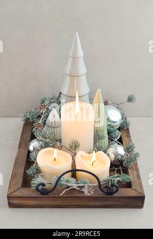Decorative ceramic fir trees with blue christmas balls   and candles on wooden tray on dark wooden background Stock Photo