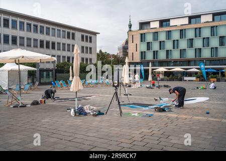 Kaiserslautern, Germany. 28th June, 2023. Stiftsplatz (Square) with several working artists at the end of day one. Eleven international artists from 6 countries are turning the Stiftsplatz (Square) pavement into three-dimensional art. 3D street art uses perspective to create optical illusion of space. Visitors are welcome to watch all artists at work over three days from Wednesday at 8:00 AM to Friday 6:00 PM. This years topic is 'Digitalisation and Smart City'. Paintings will depict robots, data, or cyberpunk scenarios. Credit: Gustav Zygmund/Alamy News Stock Photo