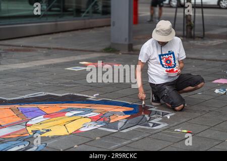 Kaiserslautern, Germany. 28th June, 2023. Milivoj Kostic painting with a brush using red colour. Eleven international artists from 6 countries are turning the Stiftsplatz (Square) pavement into three-dimensional art. 3D street art uses perspective to create optical illusion of space. Visitors are welcome to watch all artists at work over three days from Wednesday at 8:00 AM to Friday 6:00 PM. This years topic is 'Digitalisation and Smart City'. Paintings will depict robots, data, or cyberpunk scenarios. Credit: Gustav Zygmund/Alamy News Stock Photo