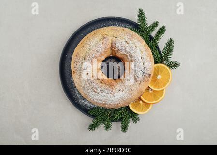 https://l450v.alamy.com/450v/2r9rd9c/top-view-of-homemade-bundt-cake-decorated-with-white-sugar-powder-orange-slises-and-fir-tree-twigs-on-black-plate-on-light-background-2r9rd9c.jpg