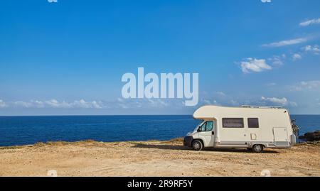 Camper rv caravan on mediterranean coast in Italy. Wild camping on sea shore. Holidays and travel in motor home. Stock Photo