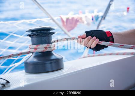 Mans hand pulling winch rope on sailing boat Stock Photo