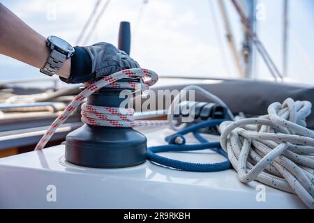 Mans hand pulling winch rope on sailing boat Stock Photo