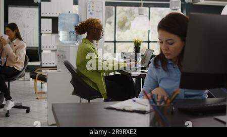 Office employee reading annual data report on screen, checking analytics before planning new company investment at desk. Young woman analyzing internet statistics, profit growth. Stock Photo
