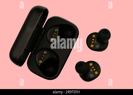 Wireless stereo earbuds. Black wireless earphones and charging case. Earbuds or headphones and charging case with bult-in rechargeable battery for the Stock Photo