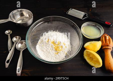 Mixing Bowl Filled with Sweet Lemon Glaze Ingredients: Glass mixing bowl with lemon glaze ingredients and kitchen tools Stock Photo