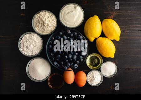 Blueberry Muffins with Lemon Glaze on a Dark Wood Background: Fresh blueberries, lemons, and other raw ingredients on a rustic wooden background Stock Photo