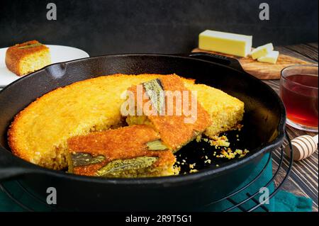 Sage Cornbread Cut Into Pieces in a Cast-Iron Skillet: Freshly baked Southern buttermilk cornbread in a frying pan with butter and honey Stock Photo