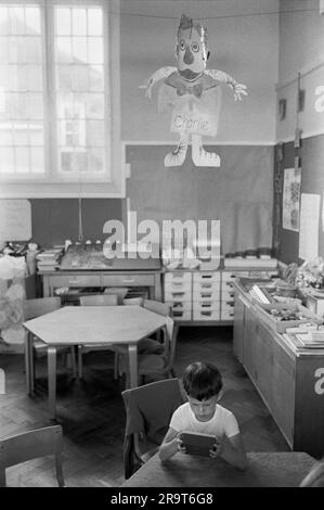 Naughty child at village primary school 1970s UK. This young boy had been bad and was made to stay in and punished. He had been a 'Proper Charlie'. A common expression at the time for someone who had been silly or stupid. He had to sit under a paper cut out figure of Charlie as punishment. Cheveley, Cambridgeshire, England 1978. HOMER SYKES Stock Photo