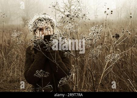 Green witch walking through snow covered marsh. Layered image with creative coloring. Stock Photo