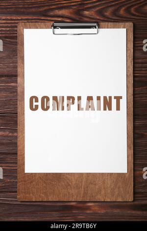 Paper with word Complaint attached to clipboard on wooden table, top view Stock Photo