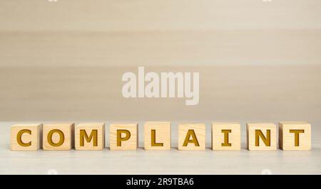 Word Complaint made of cubes on light wooden table. Space for text Stock Photo