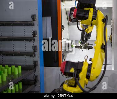 Automated manufacturing process. Robot arm loading workpieces on CNC lathe machine. Stock Photo