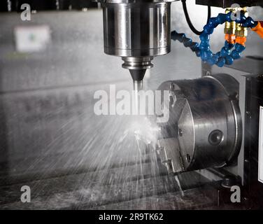 High precision CNC milling machine cutting workpiece with coolant. Industrial manufacture. Stock Photo
