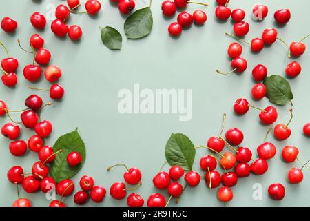 Frame made of sweet cherries and leaves on green background Stock Photo