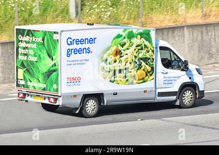 Electric powered Tesco supermarket food supply chain retail business delivery of online grocery shopping order by van driving on M25 motorway road UK Stock Photo