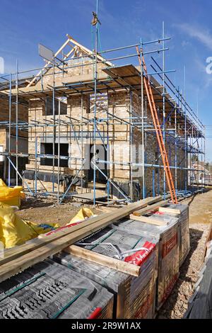 Marley concrete tiles in plastic wrap roof truss carpentry & brick gable end under construction on new build detached residential property England UK Stock Photo