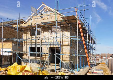 New build detached residential property with superstructure brick walls progressing at gable end with timber roof trusses fixed in position England UK Stock Photo