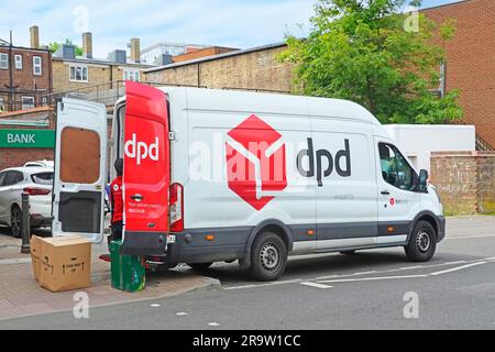 Side back view rear open doors of red white DPD parcel delivery van driver sorting parcels high street retail businesses via back entrances England UK Stock Photo