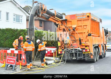 Suction excavator machine on hgv lorry truck & red hat driver holds  remote control working with two gas contractors exposing house gas connection UK Stock Photo