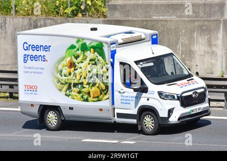 Electric powered Tesco supermarket food supply chain retail business delivery of online grocery shopping order van driving along M25 motorway road UK Stock Photo