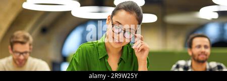 Never stop learning. Focused asian woman wearing eyeglasses making some notes while studying with colleagues during corporate training or seminar Stock Photo