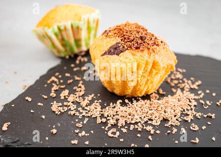 Chocolate chip cupcake with sprinkled grated chocolate, on a black stone slab, soft focus close up Stock Photo