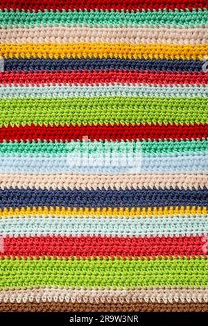 Red, green, blue, beige, aqua, brown, yellow and navy rows, horizontal multi colored crochet lines pattern, abstract close up background Stock Photo