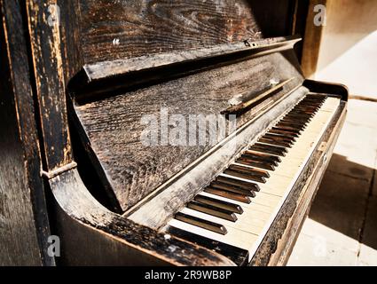 Old piano with weathered wood, peeling paint and worn keys Stock Photo