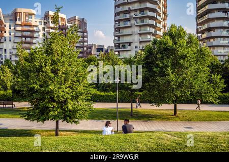 Two people sitting on the grass, reading and relaxing, in the park of Milano CityLife district. Stock Photo