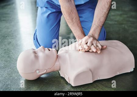 cropped view of professional healthcare worker doing chest compressions on CPR manikin, cardiopulmonary resuscitation, life-saving skills and emergenc Stock Photo