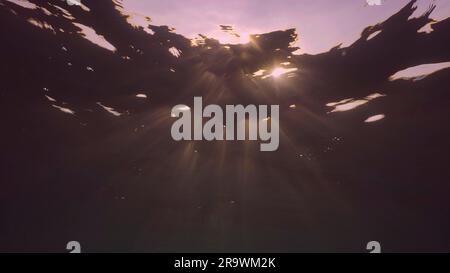 Evening sunlight creates beautiful veil, consisting of sunlight at sunset. Underwater ocean waves oscillate and flow with rays of light at sundown Stock Photo