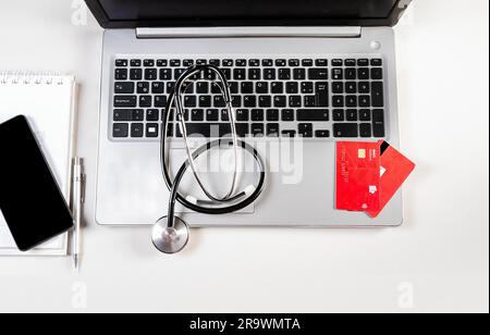 Stethoscope with credit cards on keyboard. Stethoscope on laptop keyboard with credit cards Stock Photo