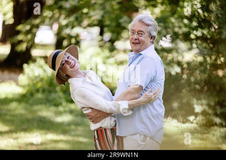 Germany, older couple dressed for summer, hugging and having fun in nature Stock Photo