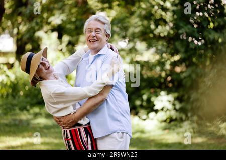 Germany, older couple dressed for summer, hugging and having fun in nature Stock Photo