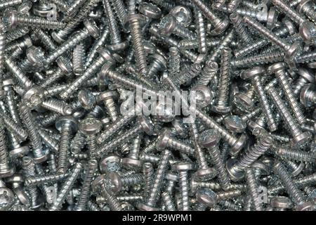 Six-lobe metal Torx screws scattered loosely. Work tools and hardware accessories, directly above view. Stock Photo