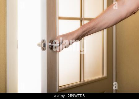 A man is opening a door leading to the light hoping for a brighter future Stock Photo