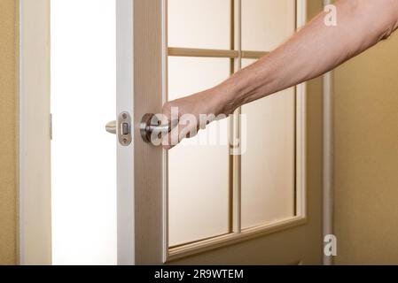 A man is opening a door leading to the light hoping for a brighter future Stock Photo