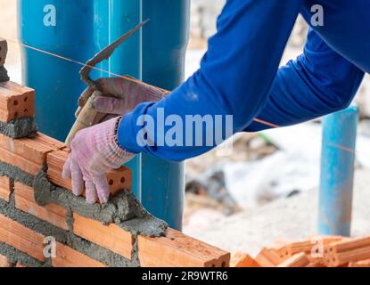 Masonry worker make concrete wall by clay brick and plaster at construction site Stock Photo