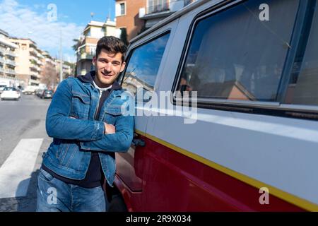 Happy young man leaning at the retro mini van Stock Photo