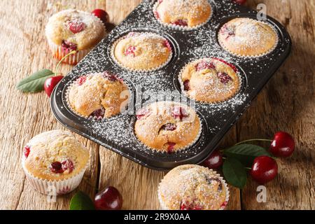 Homemade sweet and sour muffins with fresh cherries close-up in a muffin tin on the table. Horizontal Stock Photo
